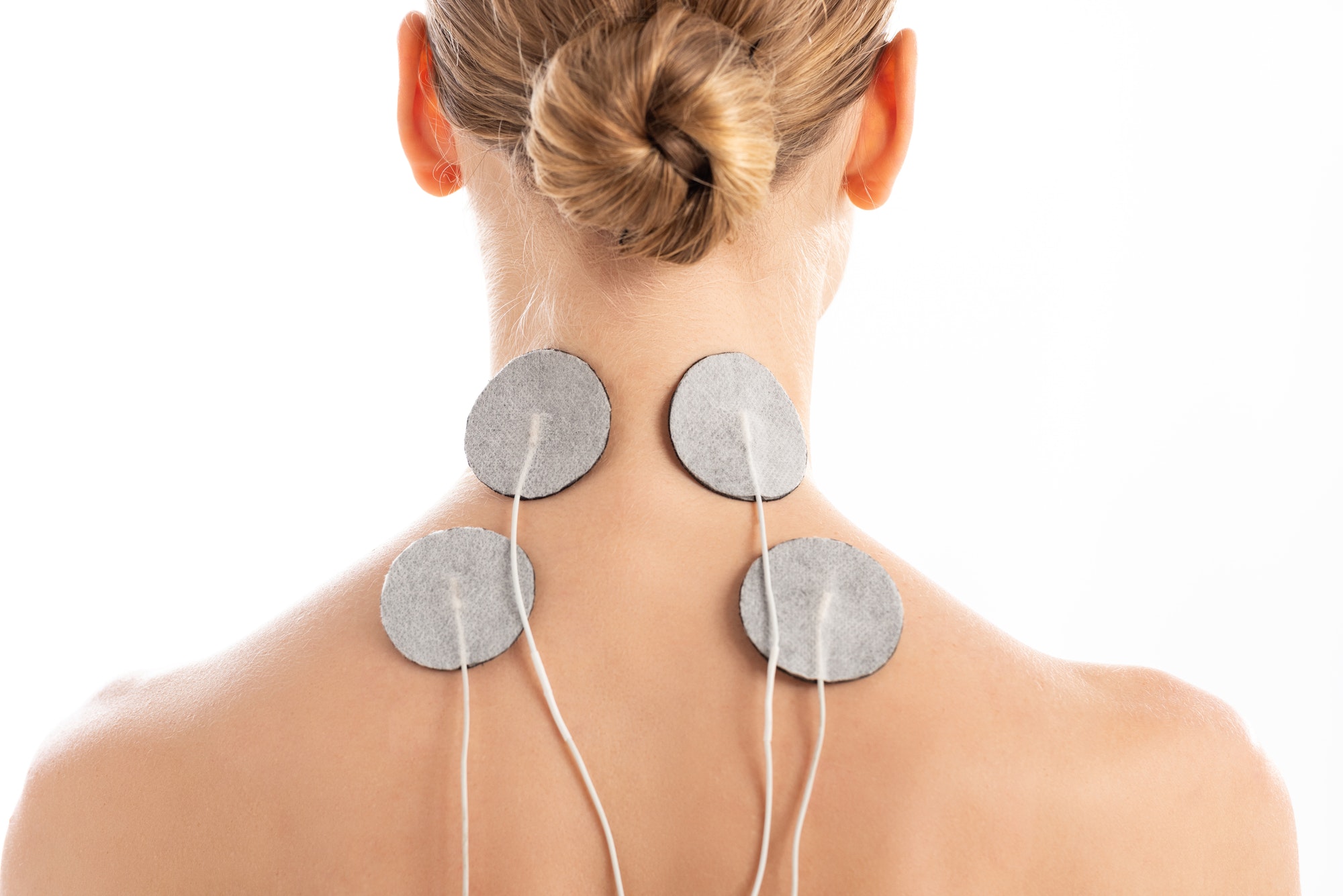 Back view of young woman with electro stimulation electrodes on neck isolated on white